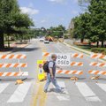 David Stowers, a University of Arkansas employee, crosses Maple Street on Monday while a crew from t...