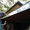 Sean Paquin caulks nail heads while Matt Poe braces the ladder earlier this month. University of Ark...