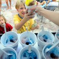 Allie Miller, right, hands Luke Koon, 7, center, a swirl-flavored snow cone Wednesday as brothers Ja...