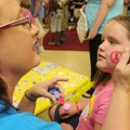 PEACE PAINT - Argie Wheeler, left, paints a peace sign on Hanna Smith, 8, during the Bentonville Adv...