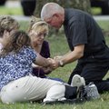 A priest kneels in prayer with three women outside Manchester High School, a gathering point for the...