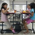 Jiji Correa, left, takes a bite of her lunch Wednesday while sitting with cousins Neida Rogo, far ri...