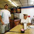 Mitch Bartholomew (left), owner of Frederick’s One Stop in Prairie Grove, chats with customer Hank G...