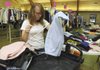 GIVING BACK - Rebekah Egle, 16, organizes clothes Thursday at the First Baptist Church in Bentonville. The church will hold its annual Clothing Giveaway from 7 to 11 a.m. Saturday at the family life center. The church is still accepting donations of gently worn clothes and shoes until noon today.
