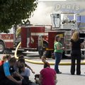 Deals employees sit in the shade Thursday while watching Rogers firefighters battle a fire that erup...