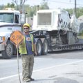 MEN AT WORK Michael Wright of Rogers, an employee of Decco Contractors & Paving, holds a sign to slo...