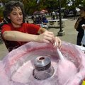 COLLEGE COMMUNITY Laurie Schuler of St. Thomas Aquinas University Parish offers cotton candy to a st...