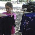 Allisun Watson, 9, of Bentonville hangs up a reverse tie-dyed T-shirt on Aug. 4 at the Benton County...