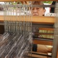 MARKET WEAVE - Genny Olson weaves an alpaca scarf Saturday at her booth at the Rogers Farmers Market...