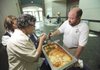 Adam Simmons, director of food services for Fayetteville Public Schools, right, works with food service technicians Linda Mellon, left, and Arlene Davis as they prepare to provide food for district teachers during an in-service day program Friday, Aug. 13, 2010, at the Fayetteville Town Center.