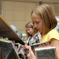 Fourth-graders Brooklyn Dostie, right, and Madison Zehnder, look for books to check out Tuesday from...