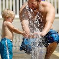Jordon Tripp and his son, Jonas Tripp, 1, play in water fountains Monday at the Rogers Splash Park o...