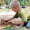 Nathan Koch, 3, of Fayetteville drives his miniature bulldozer over a recently built sand castle Mon...