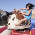 TAKING THE FALL - Third-grader Kaliegh Gallagher, 8, gets bucked off the saddle of a mechanical bull...