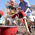 Brady O’Leary, 4, left, and Dylan Rechtfertig, 6, carry rapidly leaking buckets of water Saturday in...