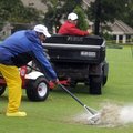 Candido Barrera, left, sweeps water off the driving range as Roberto Magaña drives a cart towing a d...