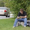 Zack Evans reads a book Monday outside of Rogers Heritage High School as he waits for his father to ...