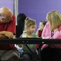 Finley Claire McClure, 5, middle, looks up at her grandmother, Kathy, as her grandfather, Donald, lo...