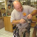 Joe Cramer with Hook, Line and Sinker in Bella Vista works on a compound bow for customer Chris Well...