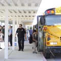 Springdale Police Sgt. Shane Pegram watches as students Wednesday get back on the school bus after a...