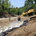A crew with Ground Zero Construction lays giant stones Friday into Spring Creek with an excavator in...