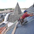 Baltazar Perea with Foster Roofing lays a layer of felt Tuesday beneath slate shingles while working...