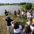 Thad Scott, left, shows a sample of the bottom of a pond to Fayetteville High School students Wednes...