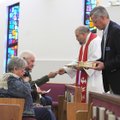  The Rev. Paul Hass and worship assistant John Hughes bring communion to worshippers at Bella Vista ...