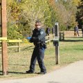 An officer from the Fayetteville Police Department stretches police line tape around the site along ...