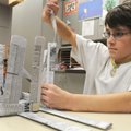 LIBRARY LEARNING - P.J. Rose, 11, of Rogers weaves together pieces of newspaper Saturday to make a b...