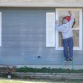CHRISTMAS DECORATIONS Jerry Clevenger reaches to hang a wreath on a window Friday at his Fayettevill...