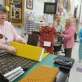 Mary Schopp, left, owner of The Rabbit’s Lair in downtown Rogers, measures fabric Friday for a custo...