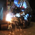 Beningo Barron welds a compactor Thursday evening at the Cram-A-Lot plant in Springdale.