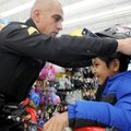 Bentonville Police Sgt. Joe Falcon fits Steven, 7, with a helmet to go with the new bike Steven pick...