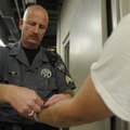 Sgt. Mike Barr places a wristband on an entering inmate Wednesday at the Benton County Jail in Bento...