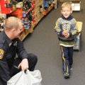 Ethan, 5, tries out a new pair of shoes Saturday with help from Rogers Police Officer John Alexander...