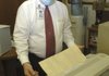 Mike Carney runs a century-old handwritten document through a machine that takes wrinkles out of the paper before it is stored for safekeeping. Carney has preserved documents that were drawn up as early as 1837.
