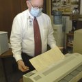 Mike Carney runs a century-old handwritten document through a machine that takes wrinkles out of the...