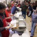 Chuck Thayer of Springdale adds turkey to a to-go box for fellow volunteer Yolanda Jones of Elkins (...