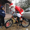  Dan Puitt, right, a.k.a. “Danta,” presents Caesar Nava, 6, with a new bicycle for Christmas on Frid...