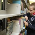 Wyatt Corbin, 7, looks for a book Thursday at the Bentonville Public Library. Many families are turn...