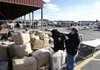 New Jersey State Police Lt. Mike McDonnell holds up a counterfeit North Face coat Dec. 9 in Columbus, N.J., near boxes of fake name-brand clothing that police seized from a flea-market vendor. 