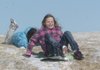 Delilah Tomlin slides in the snow Tuesday behind sledder Autumn Dorey at Greer Lingle Middle School in Rogers. A temperature in the teens and a fierce windchill didn’t deter sledders on a hill at the south side of the school. The Rogers school district canceled classes Tuesday because of the weather.