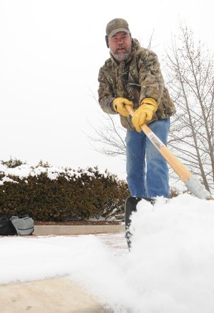 Andy Hoover shovels some of Thursday’s snow from the sidewalks Friday in front of Midtown Center in Bentonville. More light snow is possible Sunday through Tuesday for the area, according to the National Weather Service.
