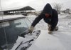 Mark Taylor scrapes a windshield Wednesday at Ryan and Susan Anglin’s Triple A Farms near Bentonville. “We can stand (the cold) all of the time. Most people can only stand it some of the time,” Ryan Anglin said as he prepared to get supplies to fix a truck clutch in the 7-degree weather Wednesday morning.