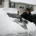 Cody Beckman of Springdale brushes more than a foot of accumulated snow from his car Wednesday morni...