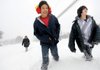 Terrell Palmer, 13, center, and Casen Hutcheson, 14, trudge through knee-deep snow early Wednesday along North Walton Boulevard in Bentonville as Terrell’s mother, Mary Hutcheson, follows. The three were headed to a nearby convenience store to get a fountain drink. “Yes, we’re crazy,” Casen said.