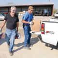 SPRING CLEANING Volunteers Jim Ecker, left, and brother John Ecker unload paint cans Saturday at the...