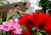 Lacie Mills takes a sniff of cinnamon basil held by William Lund of Maple Acres Farm in Bentonville at last spring’s Fayetteville Farmers’ Market. More markets open this weekend.
