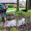 Mitchell Neukam with the Bentonville Street Department uses a shovel Saturday to clear debris from a...
